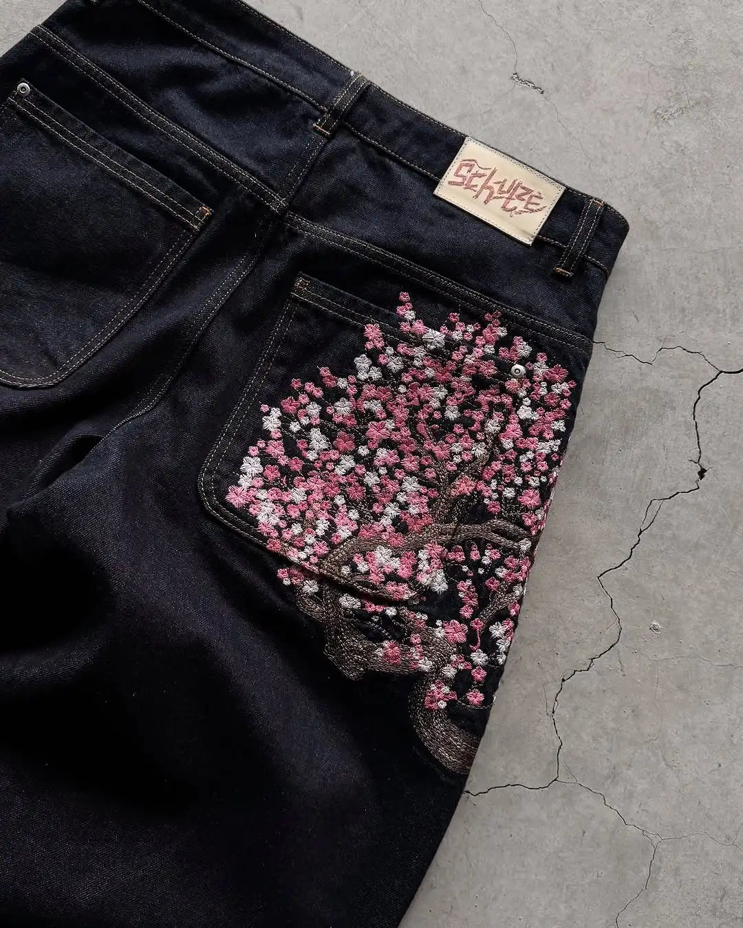 Jean homme brodé Sakura, coupe slim droite, délavage clair, coton stretch, style streetwear décontracté, plusieurs tailles disponibles.